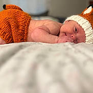 Emberleigh joined the competition — help win amazing prizes! baby, infant, knitted_hat, orange_clothing, cute, sleeping, bed, cozy, soft, newborn, face, ears, smile, lying_down, portrait, child, knitted_clothing, indoor, warm, resting