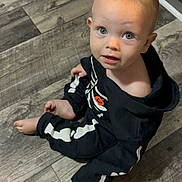 Odin is registered to the contest to win money with this photo: toddler, child, baby, floor, wooden_floor, onesie, skeleton_costume, halloween, pumpkin, barefoot, indoor, looking_up, curious, expression, face, blue_eyes, blond_hair, casual, cute, sitting