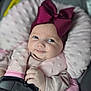 baby, infant, child, car_seat, safety_harness, pink_bow, headwear, soft_cushion, smile, cute, portrait, indoors, clothing, hand, face, eyes, baby_girl, comfort, seatbelt, closeup
