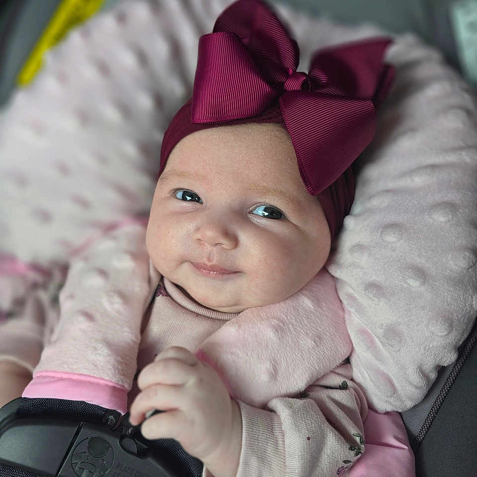 Shaylee joined the competition — help win amazing prizes! baby, baby_girl, car_seat, child, closeup, clothing, comfort, cute, eyes, face, hand, headwear, indoors, infant, pink_bow, portrait, safety_harness, seatbelt, smile, soft_cushion