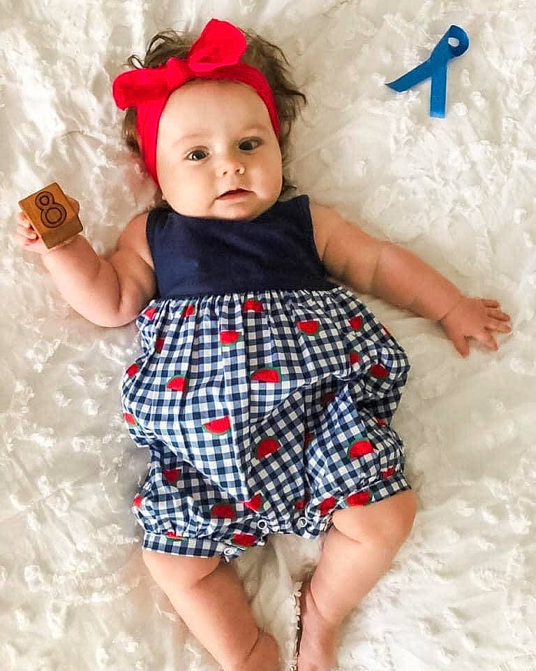 Kristen is registered to the contest to win money with this photo: arm, baby_toddler_clothing, blue, child, day_dress, dress, finger, hand, happy, headwear, leg, neck, one_piece_garment, person, pink, shoulder, skin, sleeve, textile, toddler