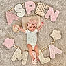 baby, baby_girl, beige, blanket, child, cozy, cute, decorative, fabric, floral_pattern, headband, infant, laying_down, letters, milestone, milestone_marker, onesie, pink, portrait, soft_toys
