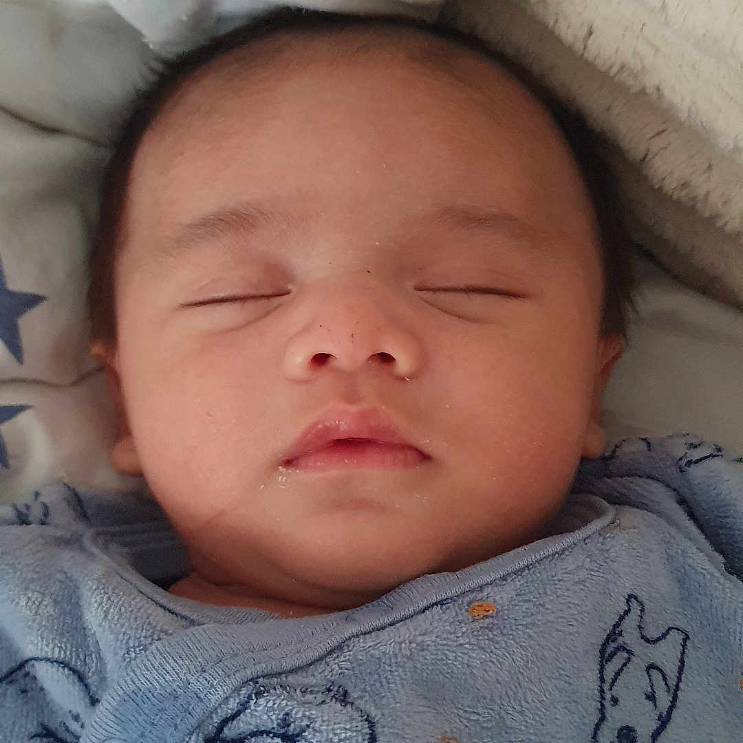 Nahyl participe au concours pour gagner de l'argent avec cette photo : animal_print, baby, blanket, blue_clothing, child, closeup, cozy, cute, face, head, indoors, infant, nap, onesie, peaceful, portrait, sleeping, soft_texture, star_pattern, text_on_clothing