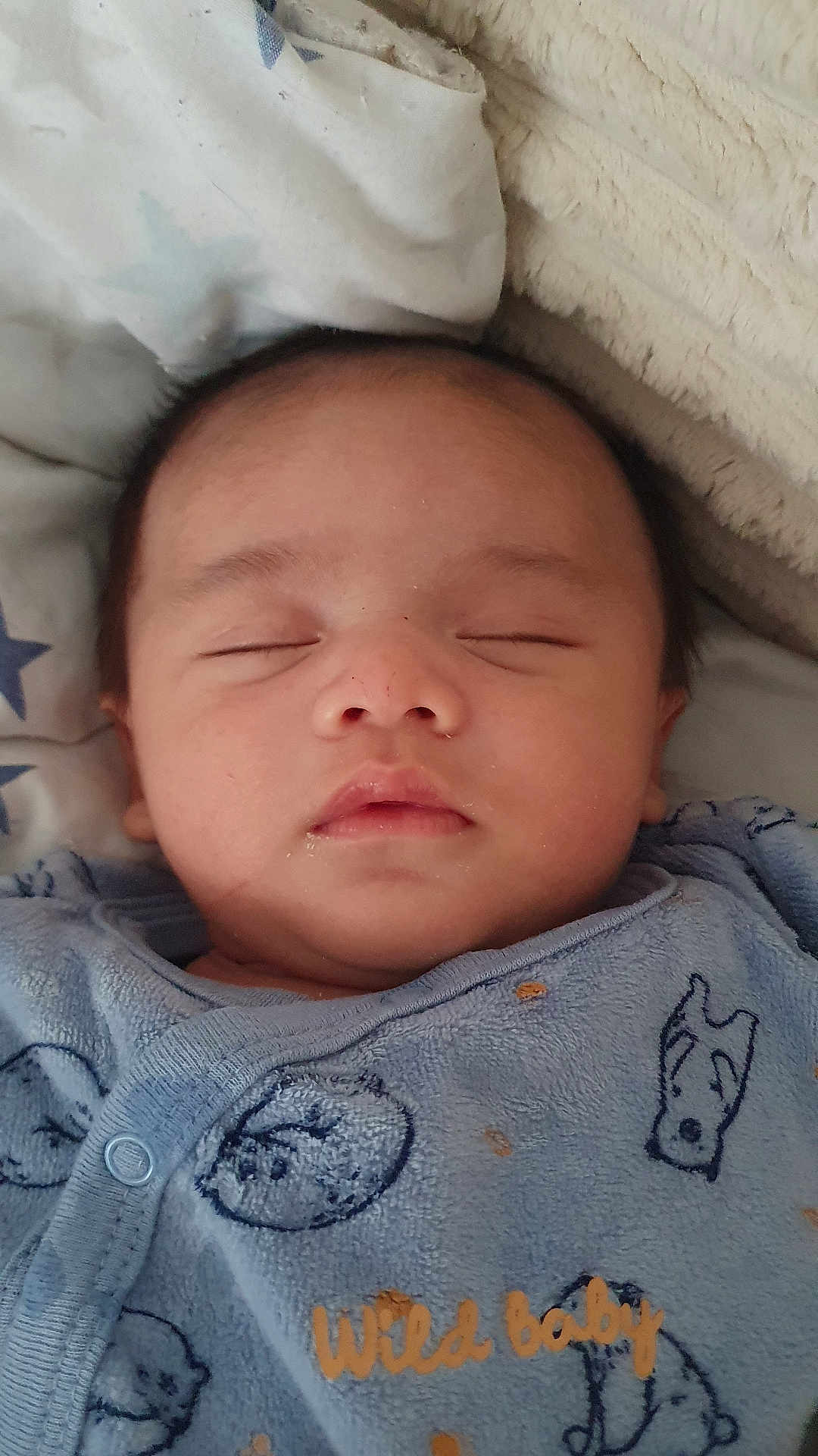 Nahyl participe au concours pour gagner de l'argent avec cette photo : baby, sleeping, onesie, blue_clothing, animal_print, text_on_clothing, blanket, star_pattern, face, infant, closeup, peaceful, soft_texture, head, portrait, child, cozy, nap, indoors, cute
