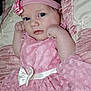 baby, infant, child, pink_dress, headband, flower, white_bow, lace, cute, portrait, closeup, soft_texture, cushion, resting, indoor, young_child, baby_girl, curious, face, skin