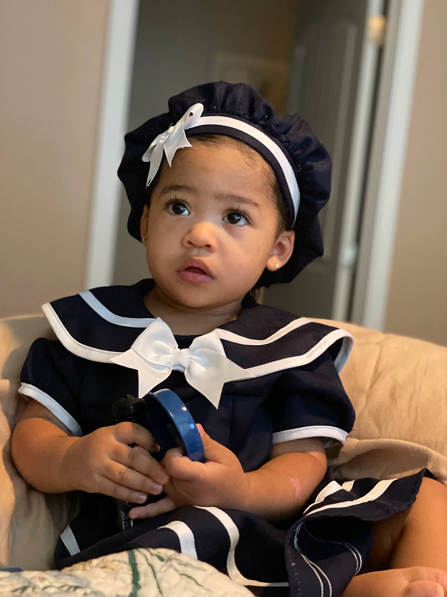 Zyana is registered to the contest to win money with this photo: arm, baby_toddler_clothing, black_hair, cap, comfort, event, eye, fashion_accessory, flash_photography, formal_wear, fun, happy, headband, headgear, person, room, sitting, sleeve, tie, toddler