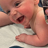 Harrison joined the competition — help win amazing prizes! baby, smiling, child, infant, face, cheeks, skin, arm, hand, medical_table, phone, photo, reflection, adult, background, happy, closeup, expression, person, healthcare