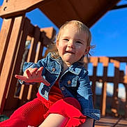 Scarlett is registered to the contest to win money with this photo: blue_sky, casual_clothing, child, closeup, cute, daytime, denim_jacket, fun, happy, outdoor, person, play, playground, portrait, red_pants, smiling, sunlight, toddler, wood, young_child