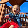 blue_sky, casual_clothing, child, closeup, cute, daytime, denim_jacket, fun, happy, outdoor, person, play, playground, portrait, red_pants, smiling, sunlight, toddler, wood, young_child