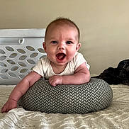 Ellis joined the competition — help win amazing prizes! baby, smiling, infant, cushion, bed, blanket, indoors, face, happy, child, person, texture, white_clothing, pattern, resting, young, cute, skin, head, arm