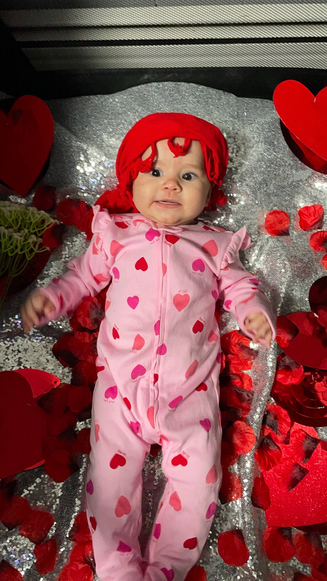 Evelyn is registered to the contest to win money with this photo: baby, bonnet, cap, clothing, coat, costume, face, flower, flowerarrangement, flowerbouquet, glove, hat, head, hood, pajamas, person, petal, photography, plant, portrait