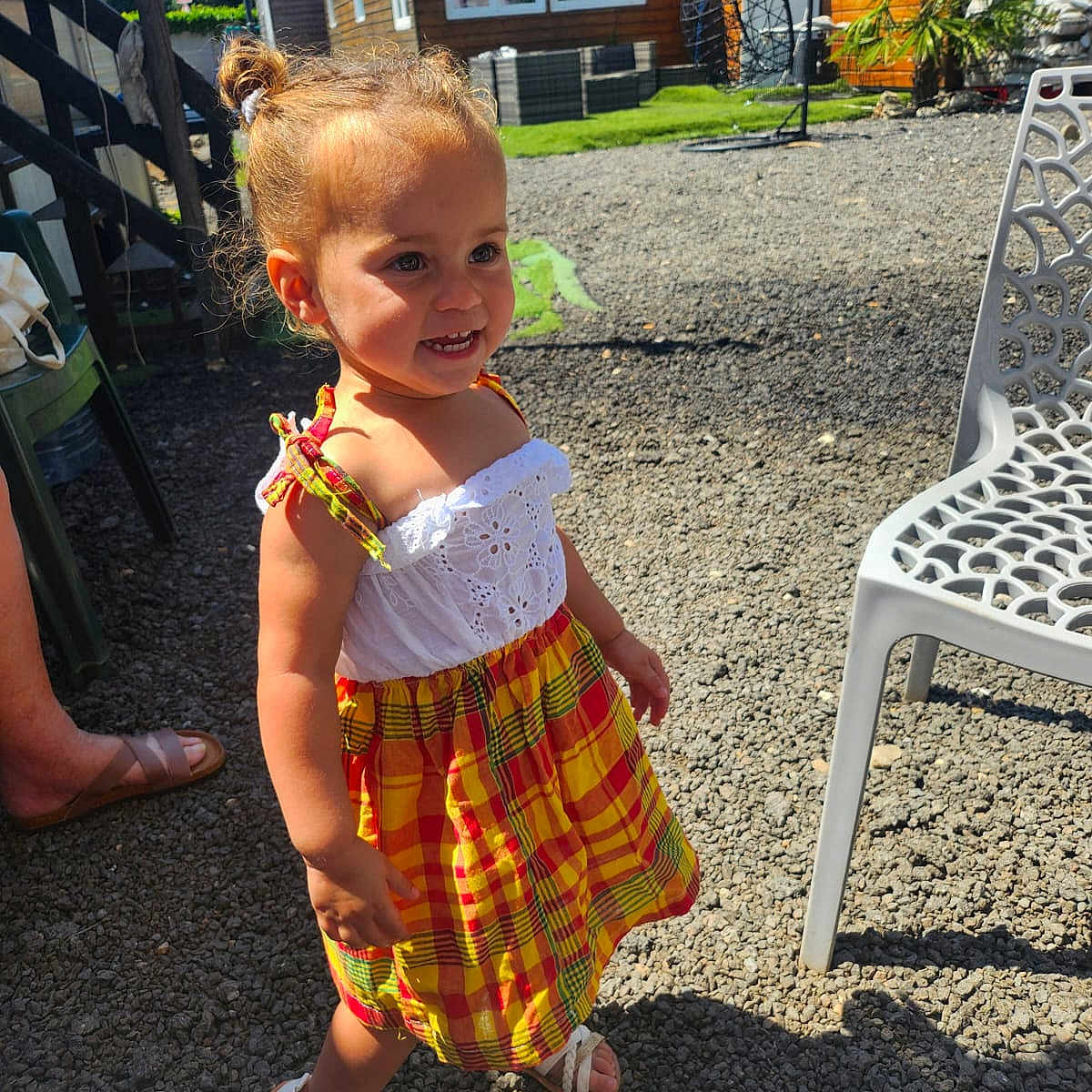 Milena a rejoint le concours — aidez-le/la à gagner de superbes lots ! chair, child, daylight, dress, footwear, garden, girl, gravel, greenery, happy, outdoor, person, pigtails, plaid, sandals, smiling, summer, sunlight, toddler, wooden_house