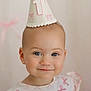 baby, child, party_hat, smile, portrait, blue_eyes, earrings, face, cute, first_birthday, pink_bows, soft_lighting, closeup, infant, celebration, young_child, apparel, headwear, happy, indoor