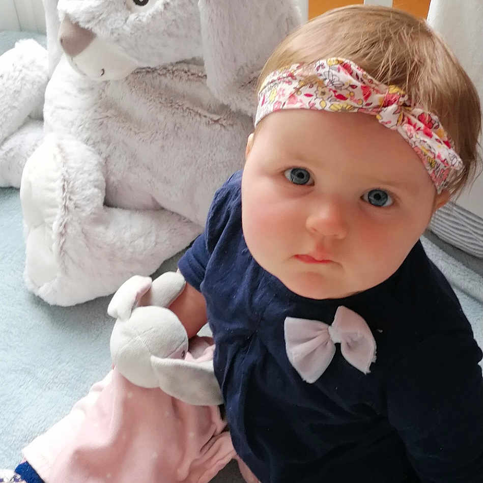 Louise a rejoint le concours — aidez-le/la à gagner de superbes lots ! baby, baby_toddler_clothing, bow_tie, cap, child, doll, embellishment, fashion_accessory, fur, grey, jewellery, pink, sitting, skin, stuffed_toy, sun_hat, toddler, toy, white, wig
