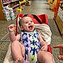 baby, shopping_cart, grocery_store, aisle, smiling, happy, infant, towel, clothing, red, person, shopping, retail, floor, shelves, products, indoor, foot, hand, face