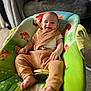 Xavier is registered to the contest to win money with this photo: baby, infant, smile, baby_seat, green, brown_clothing, bib, happy, indoors, carpet, mushroom_pattern, flower_pattern, cute, child, person, relaxing, closeup, foot, hand, comfortable