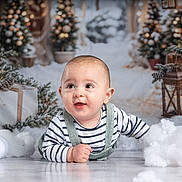 Noâh a rejoint le concours — aidez-le/la à gagner de superbes lots ! baby, child, striped_clothing, crawling, floor, christmas_tree, holiday_decor, gift_box, reindeer_decoration, snow_effect, cotton_snow, lantern, pine_cones, festive, smiling, indoor, portrait, cute, winter_theme, happy