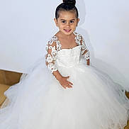 Joy participe au concours pour gagner de l'argent avec cette photo : child, girl, white_dress, lace, smiling, portrait, indoor, tiled_floor, hairstyle, bun, fashion, cute, elegant, young, person, happy, shadow, wall, formal_wear, posing