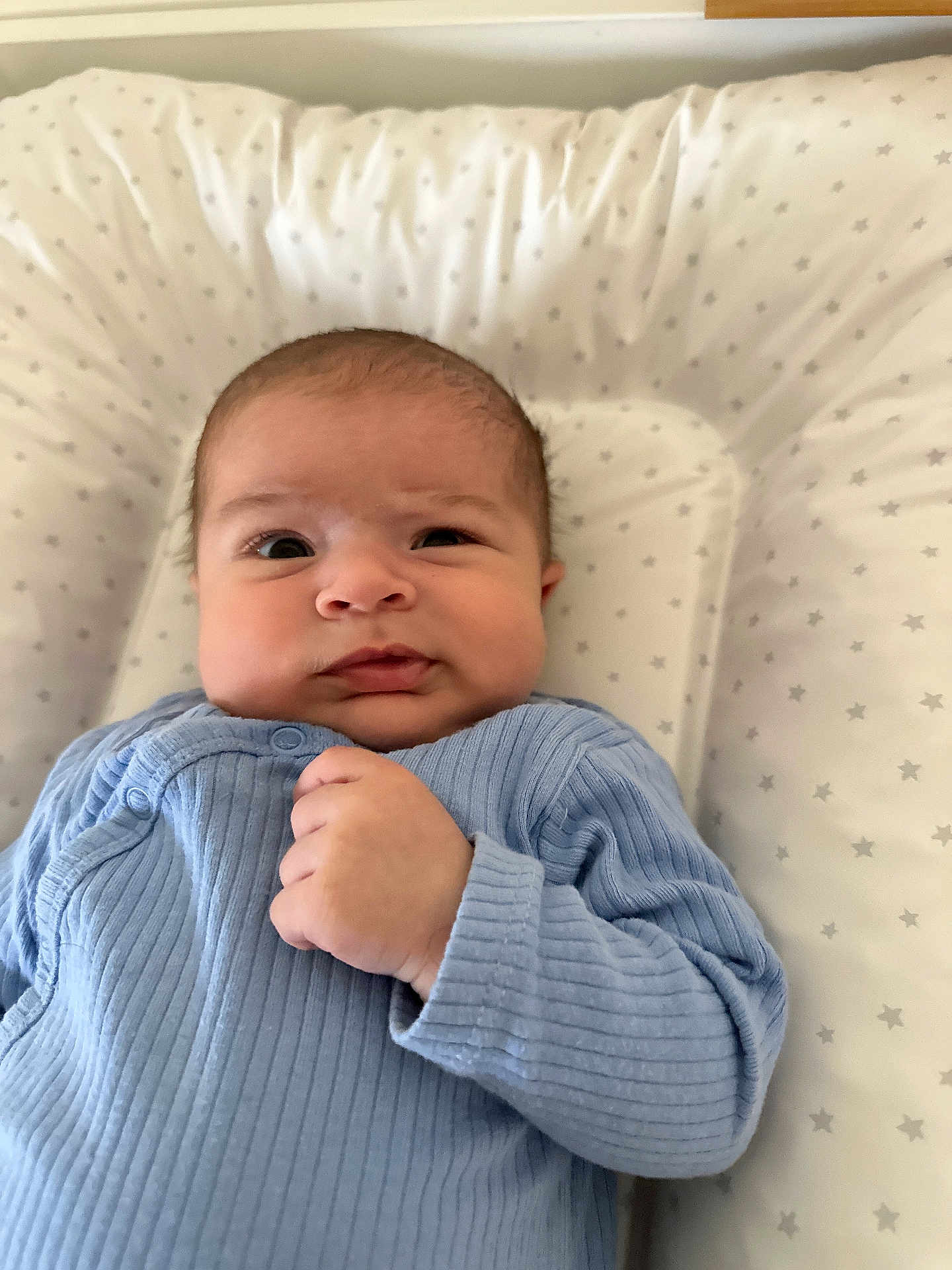 Imrân participe au concours pour gagner de l'argent avec cette photo : baby, infant, blue_onesie, face, hand, cushion, pattern, star_pattern, lying_down, close_up, skin, head, expression, indoor, newborn, child, cute, portrait, soft_fabric, comfortable