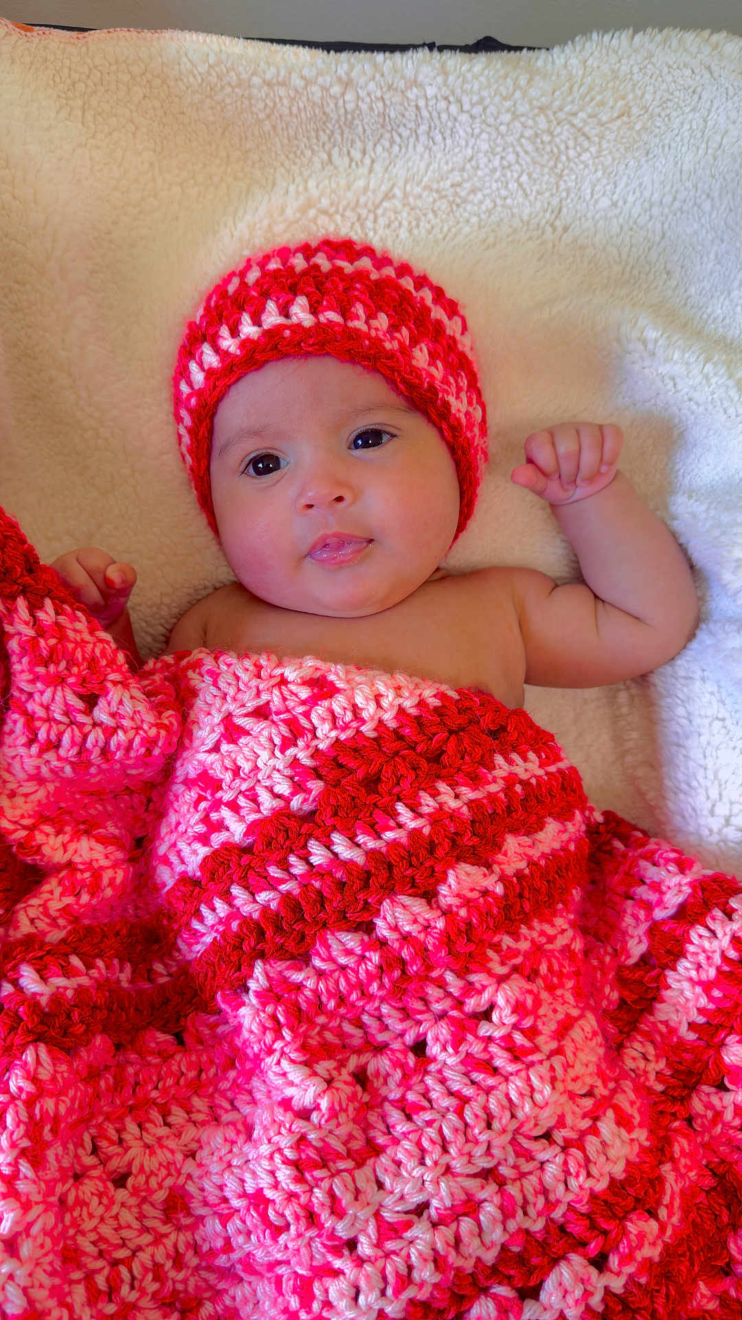 Melody Carballo Paz is registered to the contest to win money with this photo: baby, infant, blanket, crochet, hat, red, pink, cozy, cute, child, portrait, lying_down, soft, warm, face, skin, expression, indoors, resting, newborn