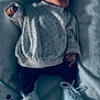 baby, newborn, sleeping, polka_dot, sweater, white_shoes, blanket, pillow, star_pattern, infant, cute, soft_texture, cozy, resting, indoors, child, footwear, clothing, person, peaceful