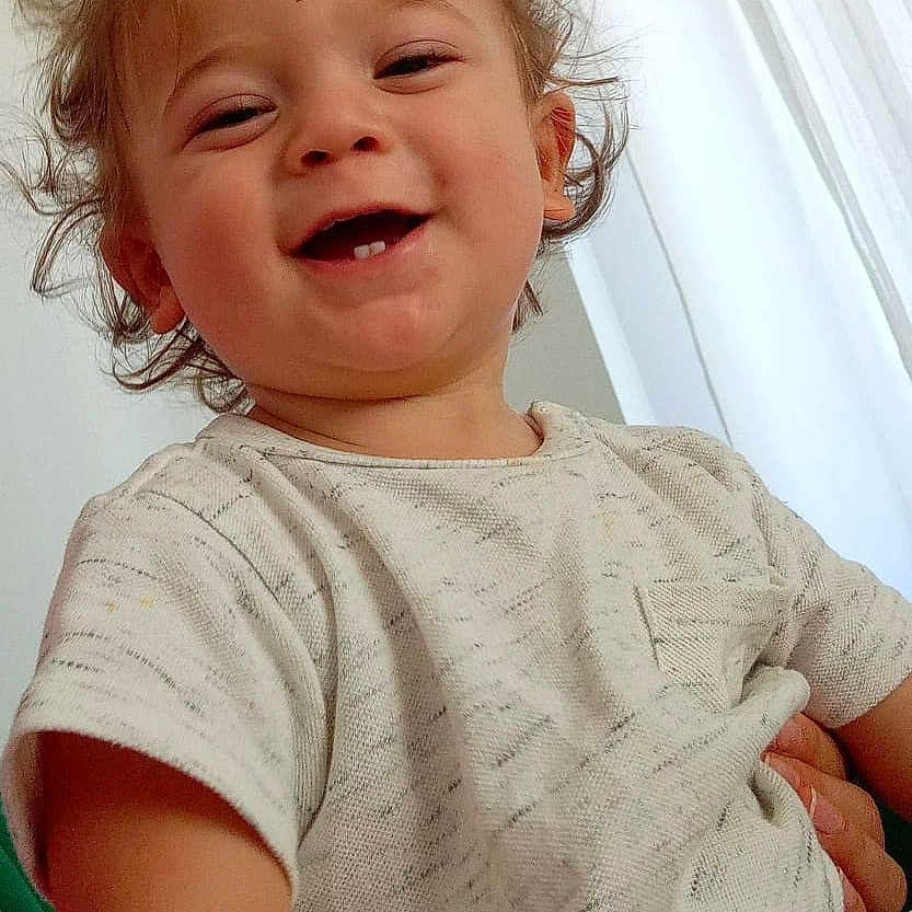 Mehmet participe au concours pour gagner de l'argent avec cette photo : baby, casual_wear, cheerful, child, close_up, curly_hair, cute, face, happy, human, indoor, light_clothing, natural_light, person, portrait, smiling, toddler, white_curtains, window, young_child