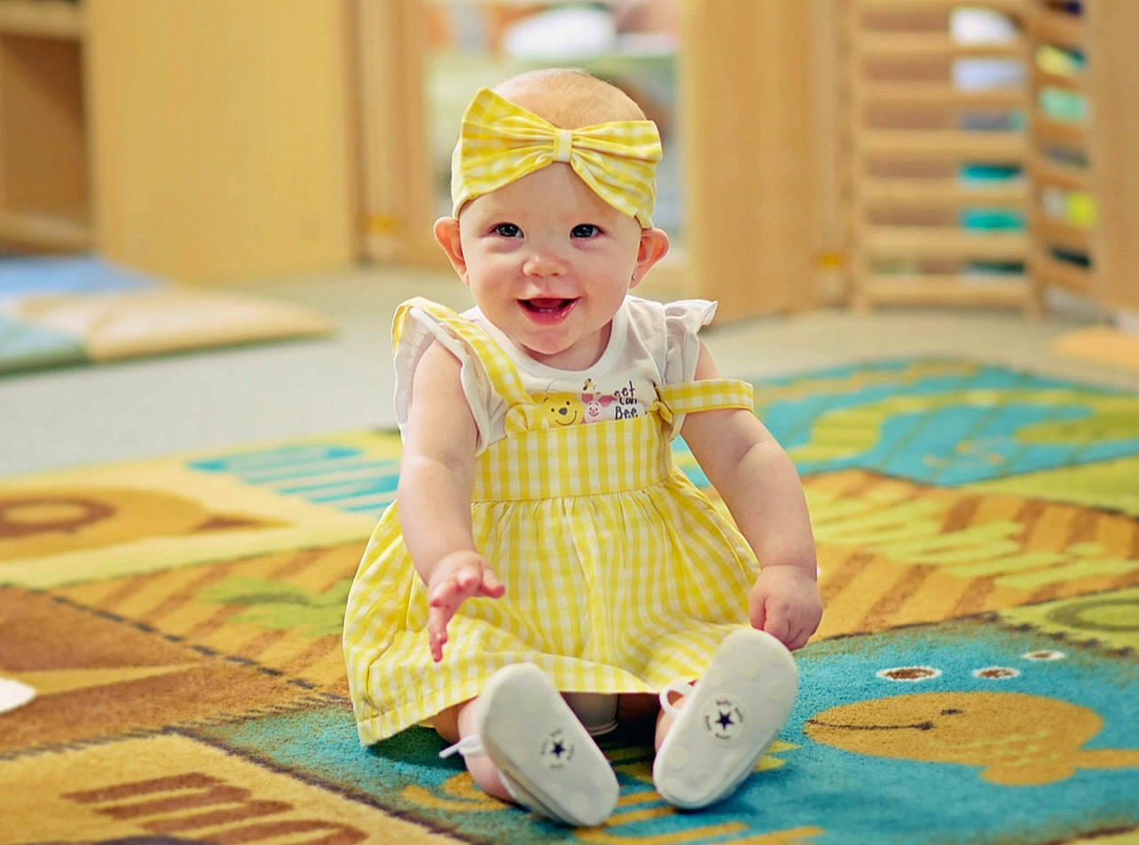 Raelyn joined the competition — help win amazing prizes! baby, baby_toddler_clothing, baby_toys, child, flooring, fun, happy, hat, headwear, leisure, pattern, person, play, room, sitting, smile, textile, toddler, wood, yellow