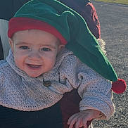 Näo participe au concours pour gagner de l'argent avec cette photo : baby, child, clothing, cute, face, festive, hand, happy, hat, headwear, infant, knitted_sweater, nature, outdoor, person, portrait, seasonal, smiling, sunlight, warm_clothing