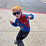 Kenneth joined the competition — help win amazing prizes! child, red_hair, sunglasses, spiderman, sweatshirt, crocs, sidewalk, street, parking_lot, car, sunny, shadow, playful, pose, tongue_out, casual_clothing, outdoor, person, fun, urban