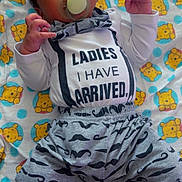 Sincere joined the competition — help win amazing prizes! newborn, baby, infant, child, portrait, lying_down, pacifier, smiling, face, eyes, hair, onesie, shirt, mustache_pattern, blanket, teddy_bear_pattern, bedroom, indoor, text_on_clothing, safe