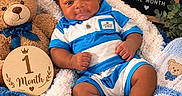 Sincere joined the competition — help win amazing prizes! baby, blanket, blue_clothing, child, close_up, cozy, happy, indoor, infant, milestone_photo, nursery, one_month, pacifier, portrait, sitting, smiling, striped_outfit, stuffed_animal, teddy_bear, wooden_sign