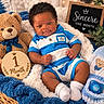baby, blanket, blue_clothing, child, close_up, cozy, happy, indoor, infant, milestone_photo, nursery, one_month, pacifier, portrait, sitting, smiling, striped_outfit, stuffed_animal, teddy_bear, wooden_sign
