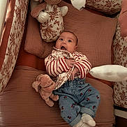 Taïana a rejoint le concours — aidez-le/la à gagner de superbes lots ! baby, infant, surprised_expression, stuffed_animal, bunny, crib, pillow, blanket, soft_toy, striped_shirt, jeans, socks, nursery, bedding, patterned_print, comforter, cute, lying_down, portrait, toy