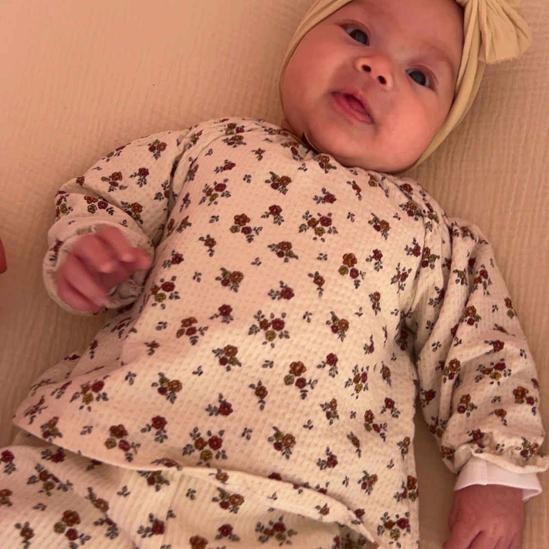 Taïana participe au concours pour gagner de l'argent avec cette photo : baby, bedding, bow, cheeks, clothing, cozy, crib, cute, face, floral_print, hand, headband, infant, lying_down, mattress, newborn, pajamas, portrait, smile, soft_lighting