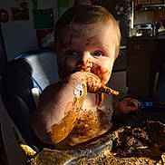 Jackson is registered to the contest to win money with this photo: toddler, child, messy, chocolate, cake, high_chair, food, face, hand, fingers, skin, kitchen, indoor, light, shadow, blue_eyes, cute, baby, smudged, eating