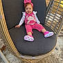 baby, child, girl, smiling, pink_outfit, headband, wicker_chair, cushion, outdoor, sunlight, happy, feet, shoes, concrete, leaves, playful, young, portrait, seated, casual