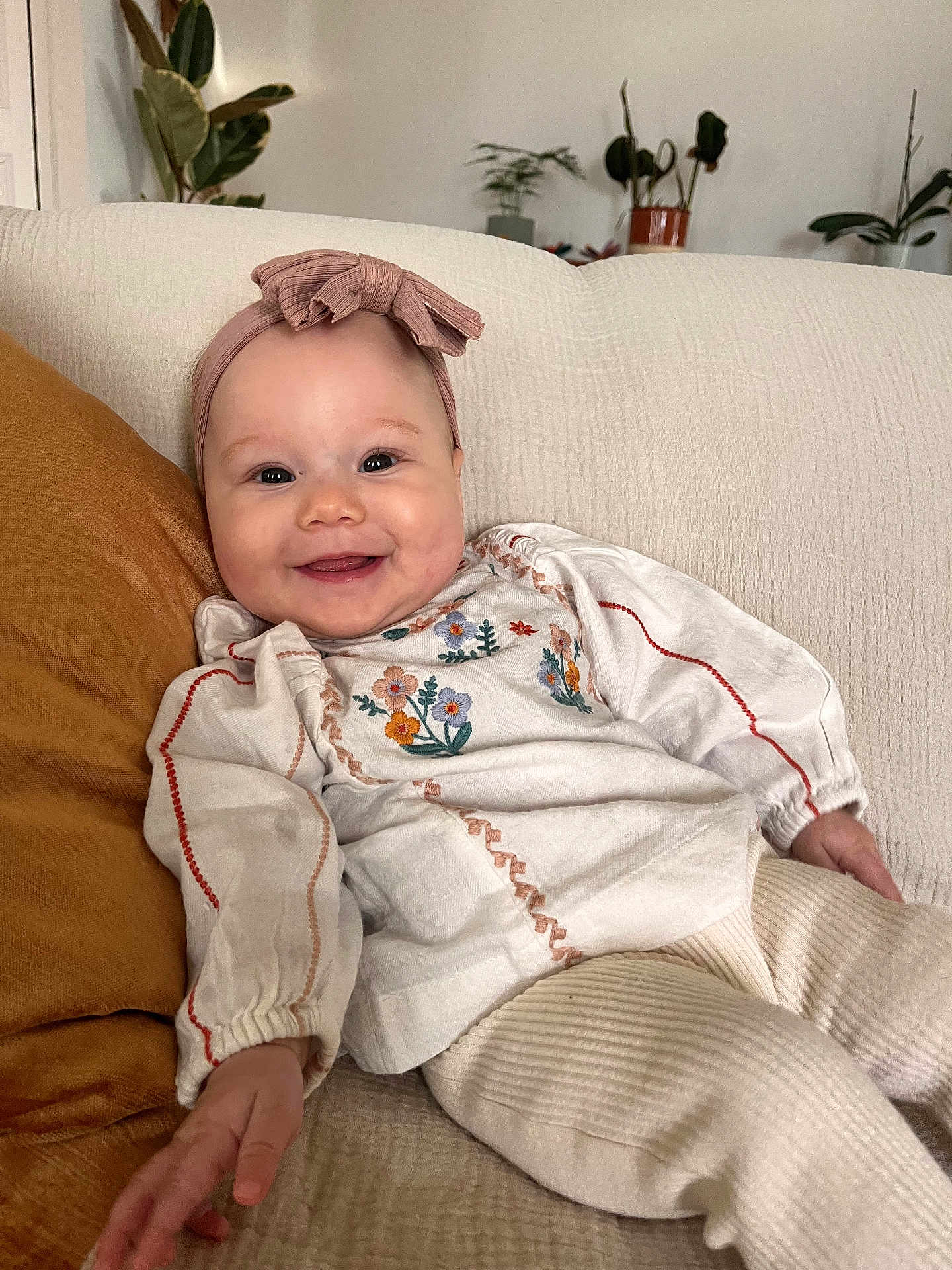 Esmée participe au concours pour gagner de l'argent avec cette photo : baby, child, smile, headband, bow, couch, pillow, plant, indoor, cozy, embroidery, clothing, person, portrait, happy, infant, furniture, relaxing, home, toddler