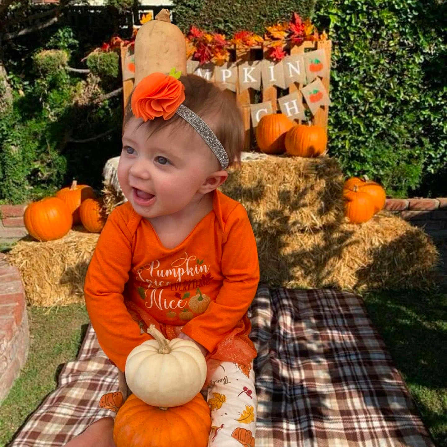 Zoey is registered to the contest to win money with this photo: autumn, baby, blanket, child, cute, decor, fall, festive, flower, garden, grass, hay_bale, headband, leaf_pattern, orange, outdoor, person, plaid, pumpkin, smiling