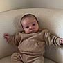 baby, infant, child, sitting, armchair, beige_clothing, knitwear, cozy, comfortable, indoor, furniture, cute, expression, portrait, young, person, sock, relaxed, head, face