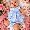 baby, child, infant, portrait, smiling, happy, blue_dress, floral_pattern, headband, flower, wicker_basket, pink_blanket, roses, flowers, soft_blanket, lying_down, indoor, pastel_colors, baby_photography, cute