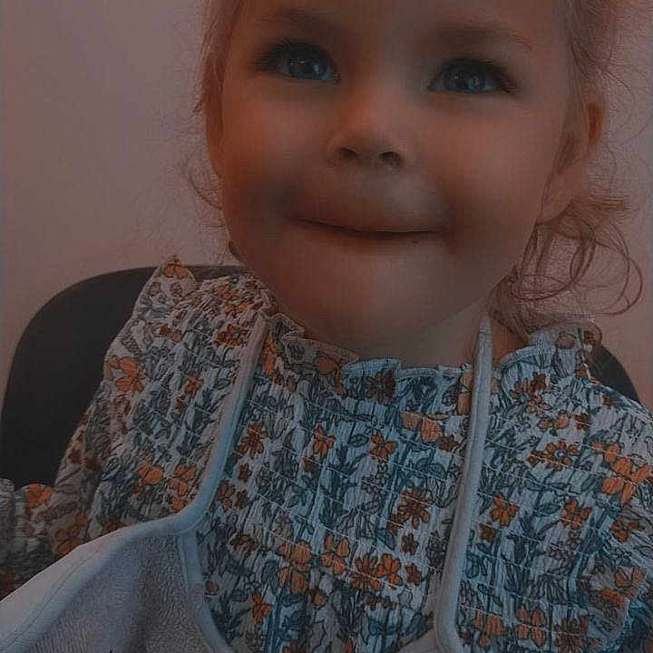 Charlotte participe au concours pour gagner de l'argent avec cette photo : baby, bib, child, childhood, closeup, clothing, cute, expression, face, floral_clothing, hair, happy, head, indoor, person, portrait, sitting, smile, young, young_child