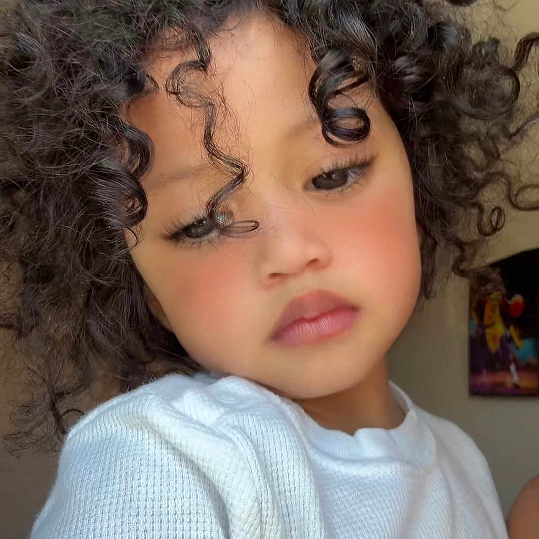 Mía Isabella Pérez joined the competition — help win amazing prizes! child, closeup, curly_hair, cute, expression, eyelashes, face, fashion, head_and_shoulders, indoor, natural_light, person, portrait, rosy_cheeks, skin, soft_lighting, toddler, warm, white_sweater, young