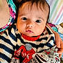 Rayyan joined the competition — help win amazing prizes! baby, infant, child, person, face, eyes, clothing, knitwear, blanket, hand, striped, pillow, bed, comfort, portrait, cute, warm, indoor, soft, holding