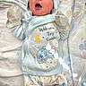 baby, newborn, yawning, blue_clothing, mittens, bunny_ears, sleepy, cute, infant, blanket, patterned_pajamas, lying_down, cozy, soft_lighting, indoors, child, adorable, cute_expression, small_hands, resting