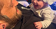 Hendrix is registered to the contest to win money with this photo: baby, man, smile, hat, indoor, lamp, beard, black_hoodie, tattoo, happy, face, person, closeup, bonding, candid, child, family, joy, affection, portrait