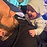 baby, man, smile, hat, indoor, lamp, beard, black_hoodie, tattoo, happy, face, person, closeup, bonding, candid, child, family, joy, affection, portrait