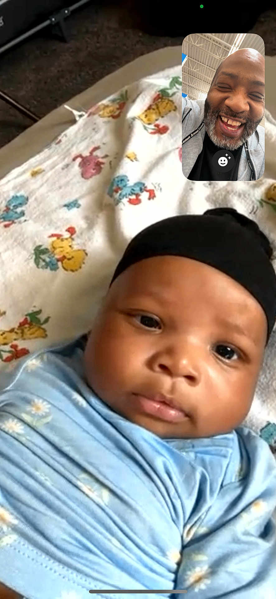 Edjen joined the competition — help win amazing prizes! baby, infant, face, swaddle, blanket, hat, closeup, video_call, inset, adult, smiling, beard, portrait, indoor, patterned_blanket, mobile_screenshot, eyes, nose, lips, family_moment