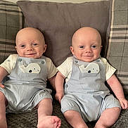 Alfie And Ethan is registered to the contest to win money with this photo: baby, infant, toddler, twins, smiling, clothing, overalls, whale_patch, couch, pillow, plaid, solid_color, blanket, feet, toes, happy, indoor, portrait, cute, child