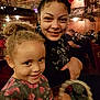 child, woman, smiling, theater, audience, curly_hair, floral_dress, seated, indoor, people, portrait, happy, family, event, crowd, casual, warm_lighting, closeup, entertainment, candid