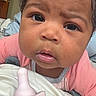 Luna joined the competition — help win amazing prizes! baby, infant, child, portrait, curly_hair, brown_eyes, serious_expression, curious, pink_clothing, pacifier, blanket, bedroom, indoor, close_up, face, head, sitting, lying_down, soft_lighting, home